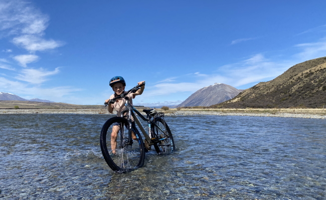 Boy pushing bike through river